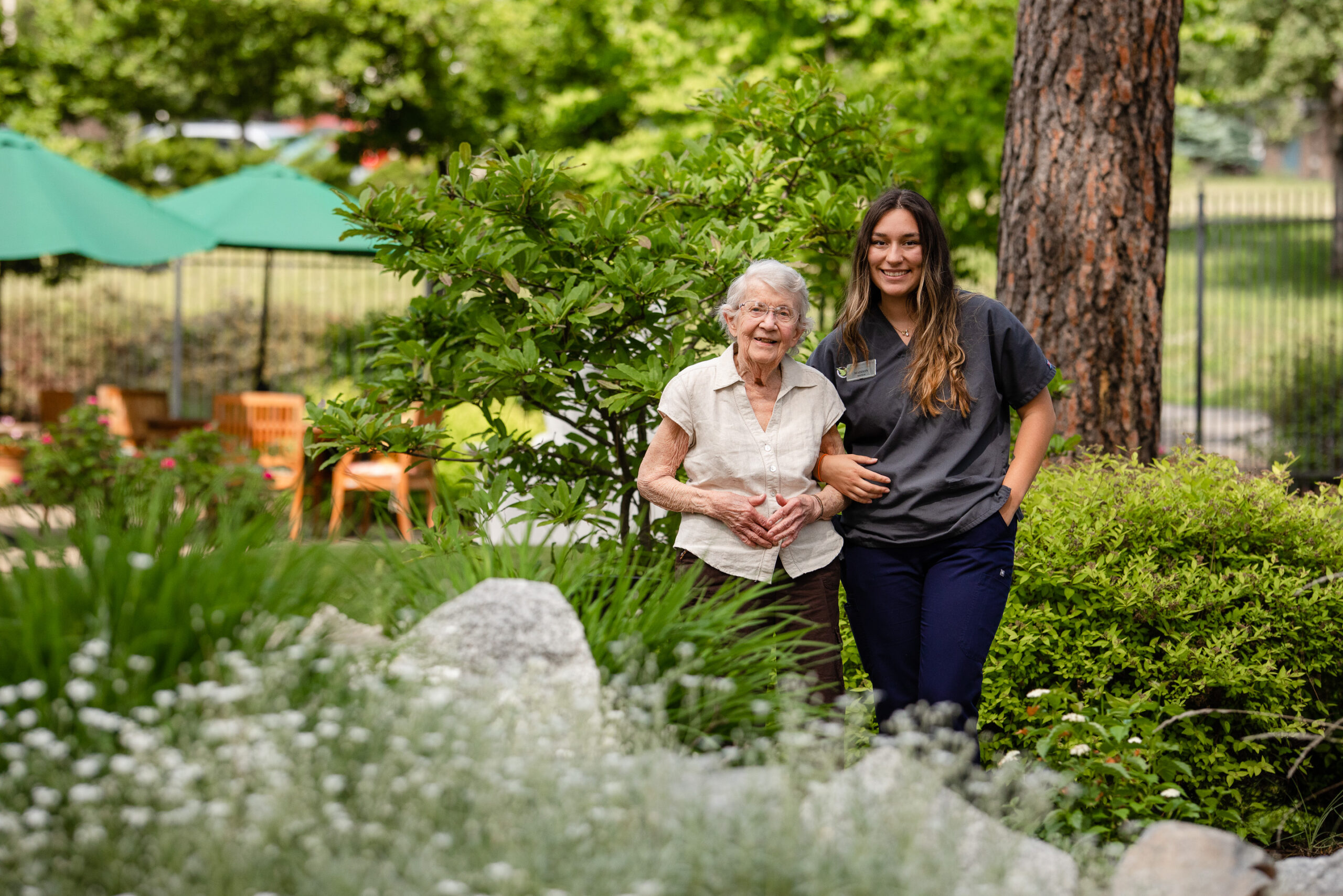 resident and caregiver standing arm-in-arm in a garden