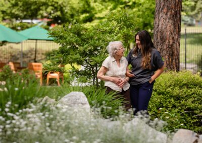 arm-in-arm resident and care giver laughing in the garden