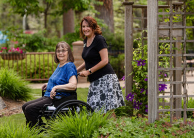 care giver pushing resident on a wheel chair through the garden